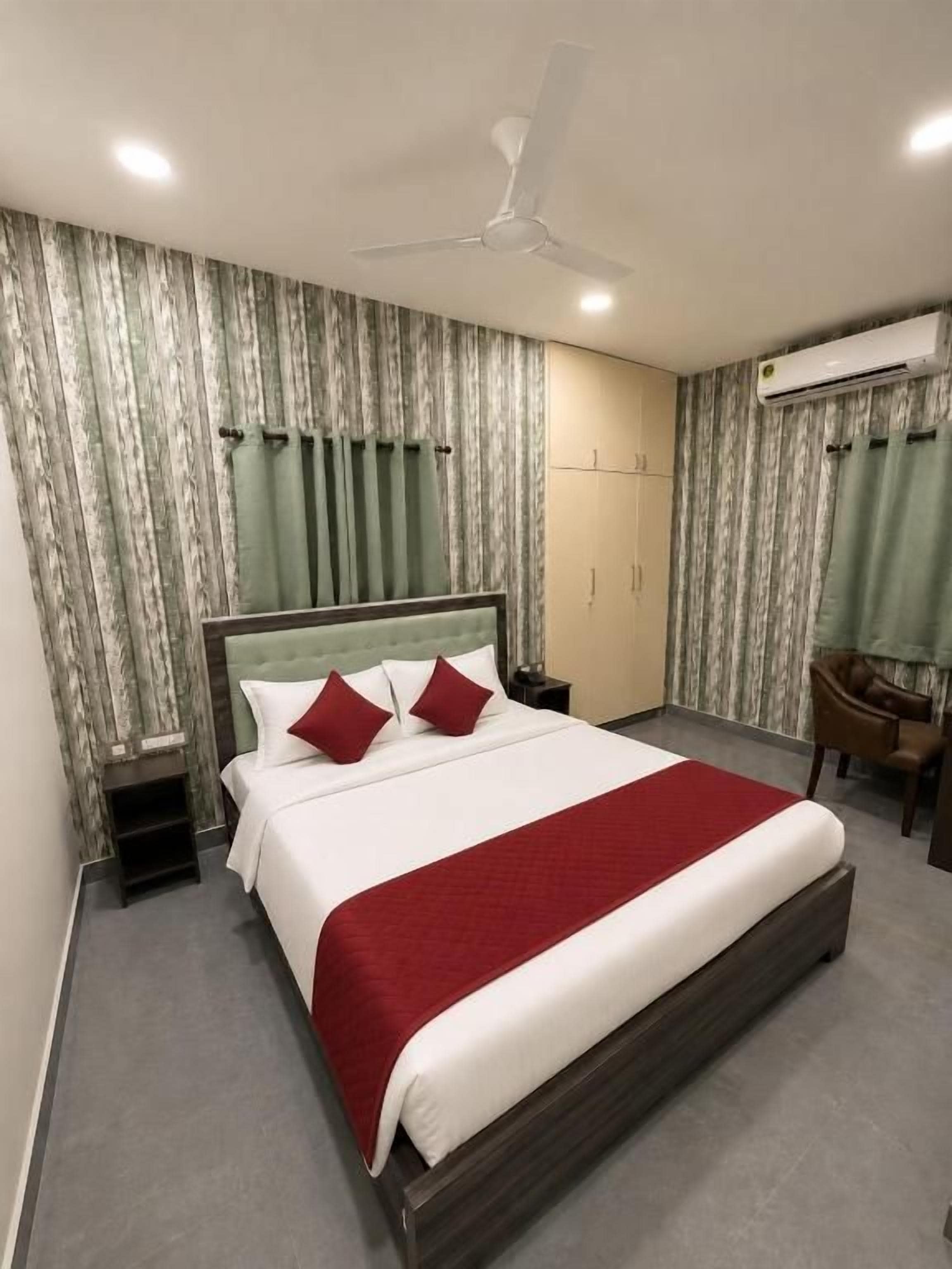 Habitación de hotel con una cama grande, ventilador de techo, aire acondicionado y un escritorio con silla.