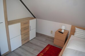 A bedroom with a bed, a nightstand, a dresser, and a red rug.