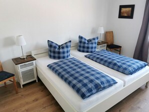 A double bed with blue checkered bedding, a bedside table with a lamp, and a small nightstand with a lamp. - Holiday Home in Amrum With 4 Bedrooms (Norddorf)