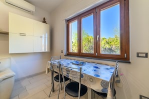 A dining area with a table set for four, a window with wooden frames, and a white cabinet above the table. - Sea House Sorrento(Near the sea) - Around Sorrento (Meta)