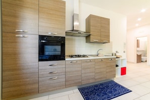 A modern kitchen with wooden cabinets, a built-in oven, a gas stove, and a stainless steel range hood. - Sea House Sorrento(Near the sea) - Around Sorrento (Meta)