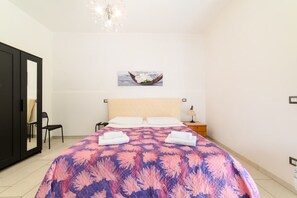 Ein Schlafzimmer mit einem Bett, einem Nachttisch, einem Sessel, einem Kleiderschrank und einem Bild an der Wand.