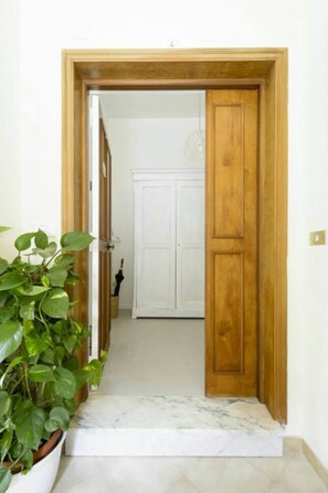 A hallway with a wooden door frame, a potted plant, and a white door in the background. - Casa Ermandina - Sorrento city center (Sorrento)
