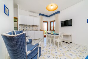 A compact living space with a kitchenette, dining area, and a television mounted on the wall. - Casa Albilore - Sorrento Coast (Sorrento)