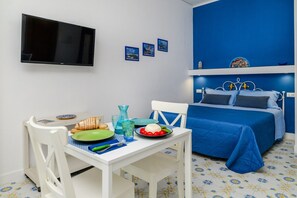A room with a bed, a table with breakfast items, a television, and a wall with pictures. - Casa Albilore - Sorrento Coast (Sorrento)