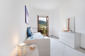 A bedroom with a bed, bedside table, dresser, and a balcony with a view. - Lux Fabulous Sorento (Sorrento)