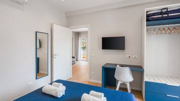 Ein Schlafzimmer mit einem Bett, einem Schreibtisch, einem Stuhl, einem Fernseher und einem Kleiderschrank.