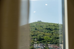 Blick auf einen Hügel mit einem Gebäude auf der Spitze, einen klaren Himmel und einen flüchtigen Blick auf ein Gebäude im Vordergrund.