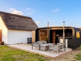 Ein Gebäude mit einem Reetdach, einer Terrasse und Sitzgelegenheiten im Freien.