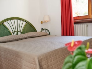 Ein Bett mit Kopfteil, eine Nachttischlampe und ein Fenster mit roten Vorhängen.