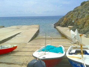 A pier with boats docked, a rocky coastline, and the sea in the background. - Holiday Apartment With 2 Bedrooms (Marciana)