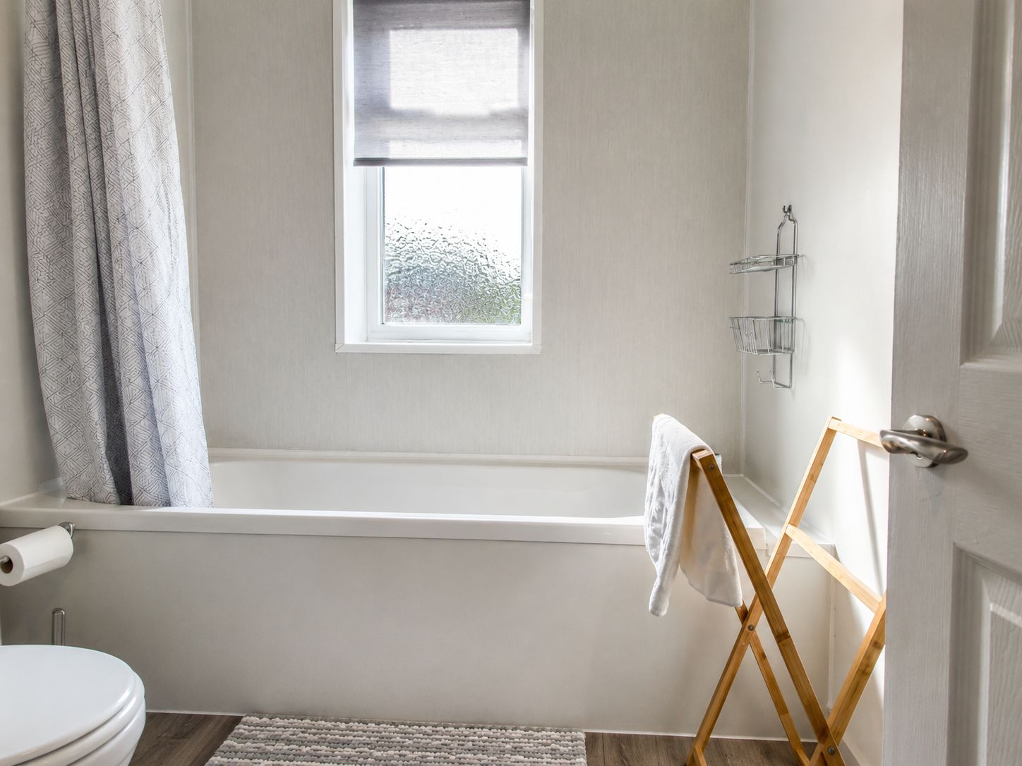 Une salle de bain avec une baignoire, une fenêtre, des toilettes et un porte-serviettes.