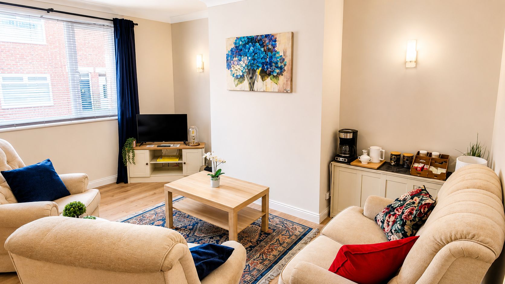 Un salon comprenant un canapé, un fauteuil, une table basse et un meuble pour la télévision, sur lequel est posée une télévision à écran plat.