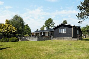 A two-story house with a porch, a covered deck, and a fenced yard. - Holiday home with large terrace in North Zealand (Vejby)