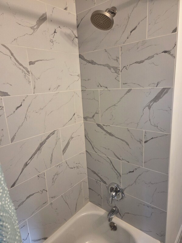 A shower with a handheld showerhead and a wall-mounted faucet. - Caulembrast Hollow 3BR House with 1.5 Bathrooms (South Euclid)