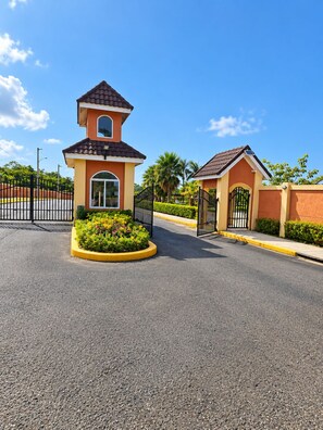 A gated entrance with a small building, a paved road, and a clear sky. - Drax Hall Oasis - 3BR Villa close to Ochi Rios (Saint Ann's Bay)