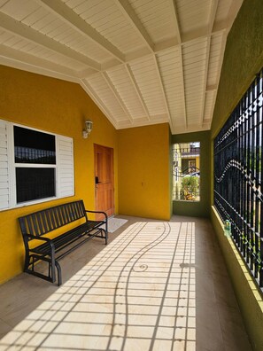 A corridor with a bench, a door, and a window with barred glass. - Drax Hall Oasis - 3BR Villa close to Ochi Rios (Saint Ann's Bay)