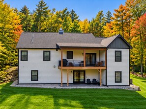 A two-story house with a balcony, a covered porch, and a well-maintained lawn. - A Lake George Favorite Home - 1 mile to LG Village (Lake George)