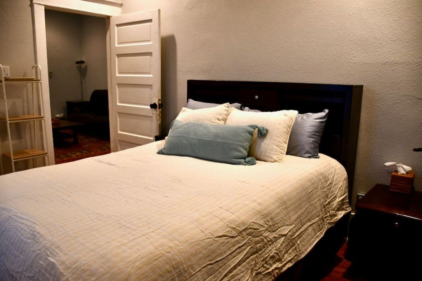 Een bed met een gewatteerde spreidek en een houten hoofdbord, voorzien van twee kussens.