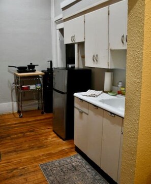 A compact kitchen with white cabinets, a black refrigerator, and a small countertop.