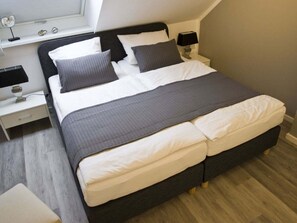 A neatly made bed with a dark headboard, two bedside tables with lamps, and a window above the bed. - Holiday Apartment With 2 Bedrooms (Groemitz)
