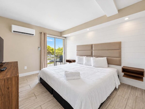 Une chambre d’hôtel moderne dotée d’un grand lit, d’une télévision et d’un balcon avec vue.