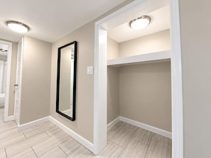 A hallway with beige walls, white trim, and light wood flooring. There is a black-framed mirror on the wall and recessed ceiling lights. - Coastal Escape at 300 Tenth | 228 (Myrtle Beach)