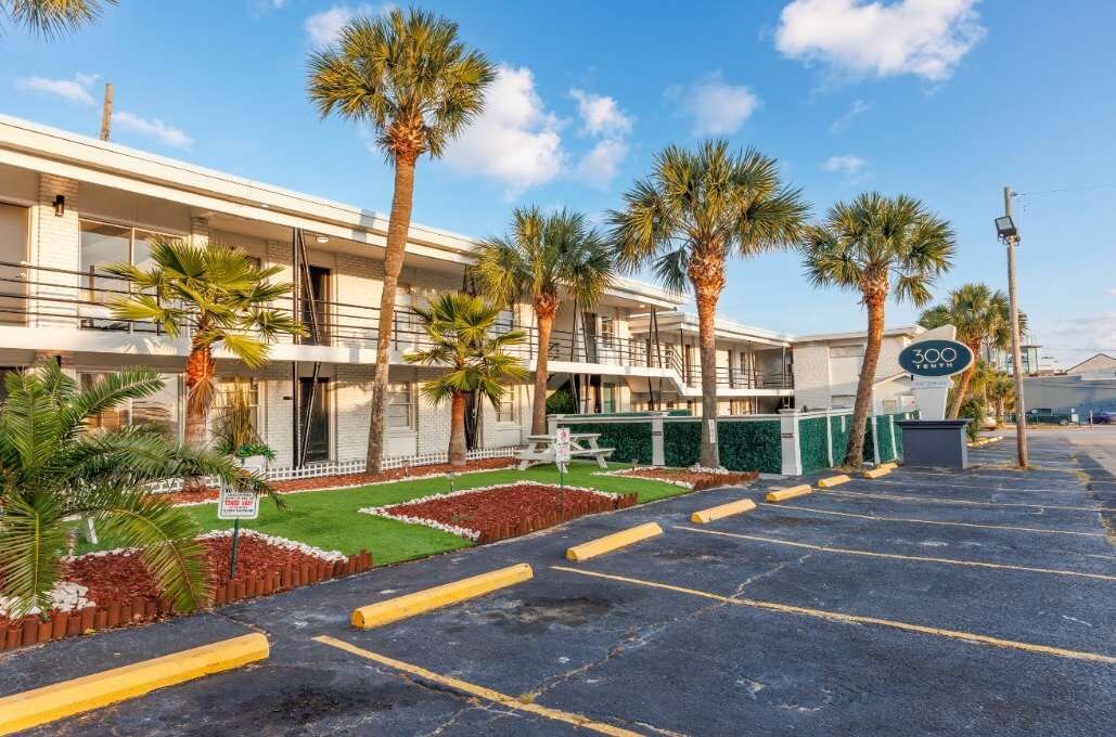 Een hotel met een parkeerplaats, palmbomen en een bord waarop staat aangegeven dat er 300 kamers zijn.