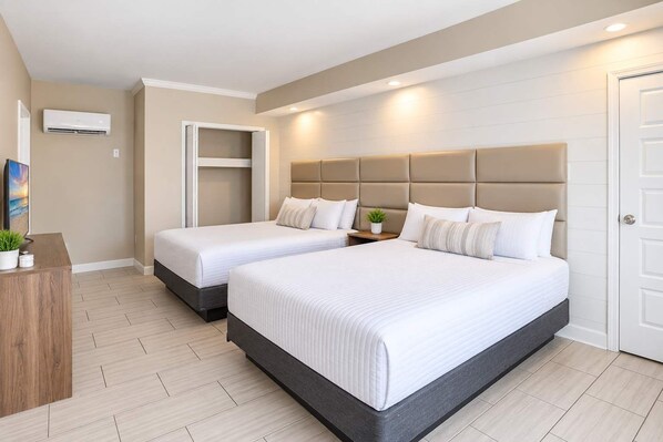 Une chambre d’hôtel avec deux lits, un bureau et un appareil de climatisation.