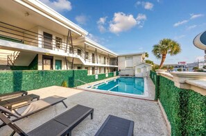 Un hôtel doté d’une piscine, d’un espace extérieur aménagé et d’un palmier.