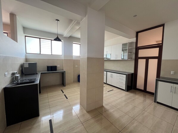 A kitchen with a dining area, a small table with a computer, and a window providing natural light.