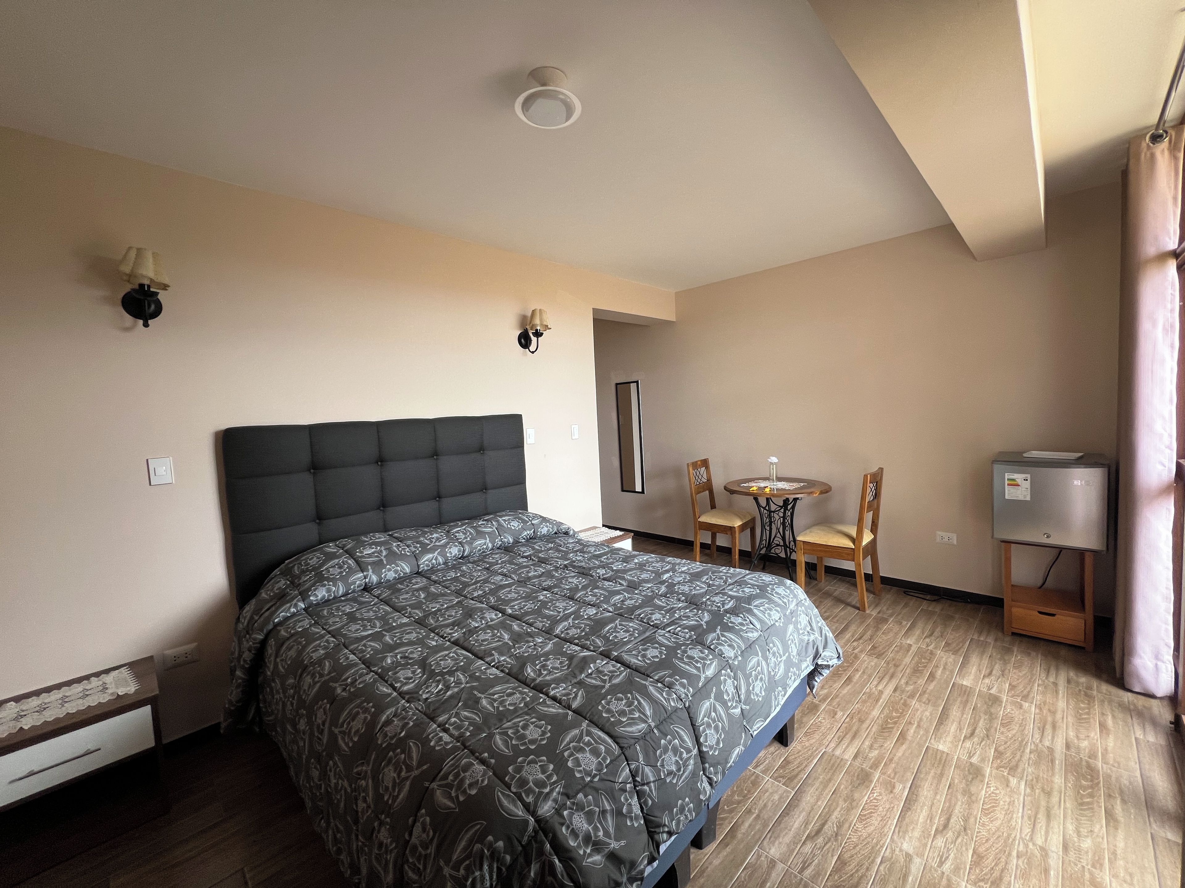 Une chambre à coucher comprenant un lit, une petite table avec des chaises, un radiateur et un luminaire fixé au mur.