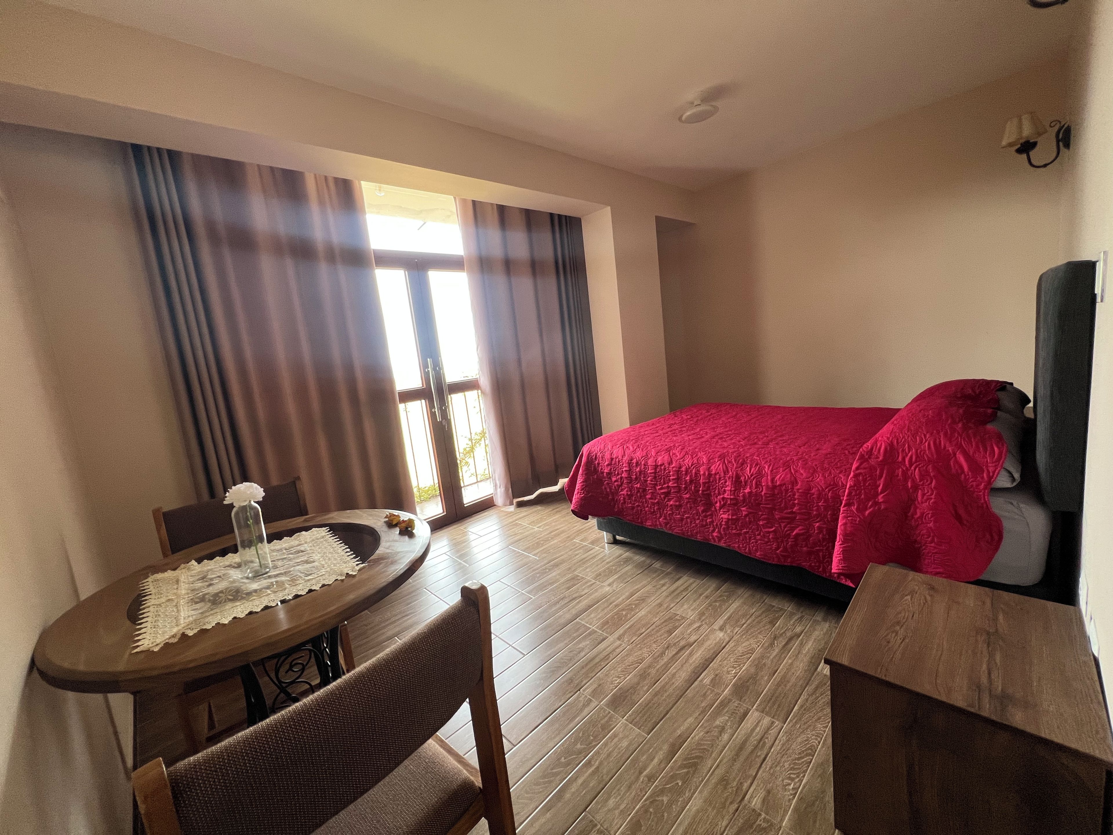Une chambre d’hôtel avec un lit, une table à manger avec des chaises et une vue par la fenêtre.