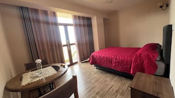 Une chambre d’hôtel avec un lit, une table à manger avec des chaises et une vue par la fenêtre.