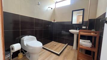 Une salle de bain comprenant des toilettes, un lavabo et un espace douche.