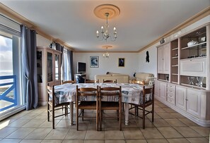 A dining area with a table set for four, a chandelier, and a view through a window.