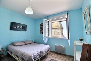 A bedroom with a bed, a window, a radiator, and a wall-mounted picture.