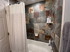 A bathroom with a bathtub, shower, and a tiled wall. - Cozy 1-bedroom condo in peaceful Park City with AC (Park City)