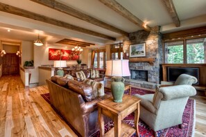 A spacious living area with a fireplace, leather sofa, and a television. - Cowboy Heaven 5 Bed Home in Big Sky | Ski In/Out (Big Sky)