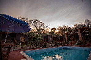 A pool area with wooden cabins and a covered seating area. - Cabins, Pool, Nature, Barbecue Area, Iguazu Falls (puerto iguazu)