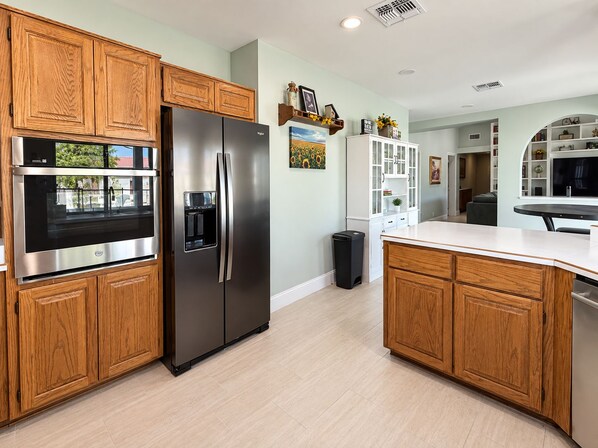 A modern kitchen with wooden cabinets, stainless steel appliances, and a white countertop. - 4 Bedroom Retreat with Pool, hot tub, outdoor kitchen, arcades, sleeps 12 (Mesa)