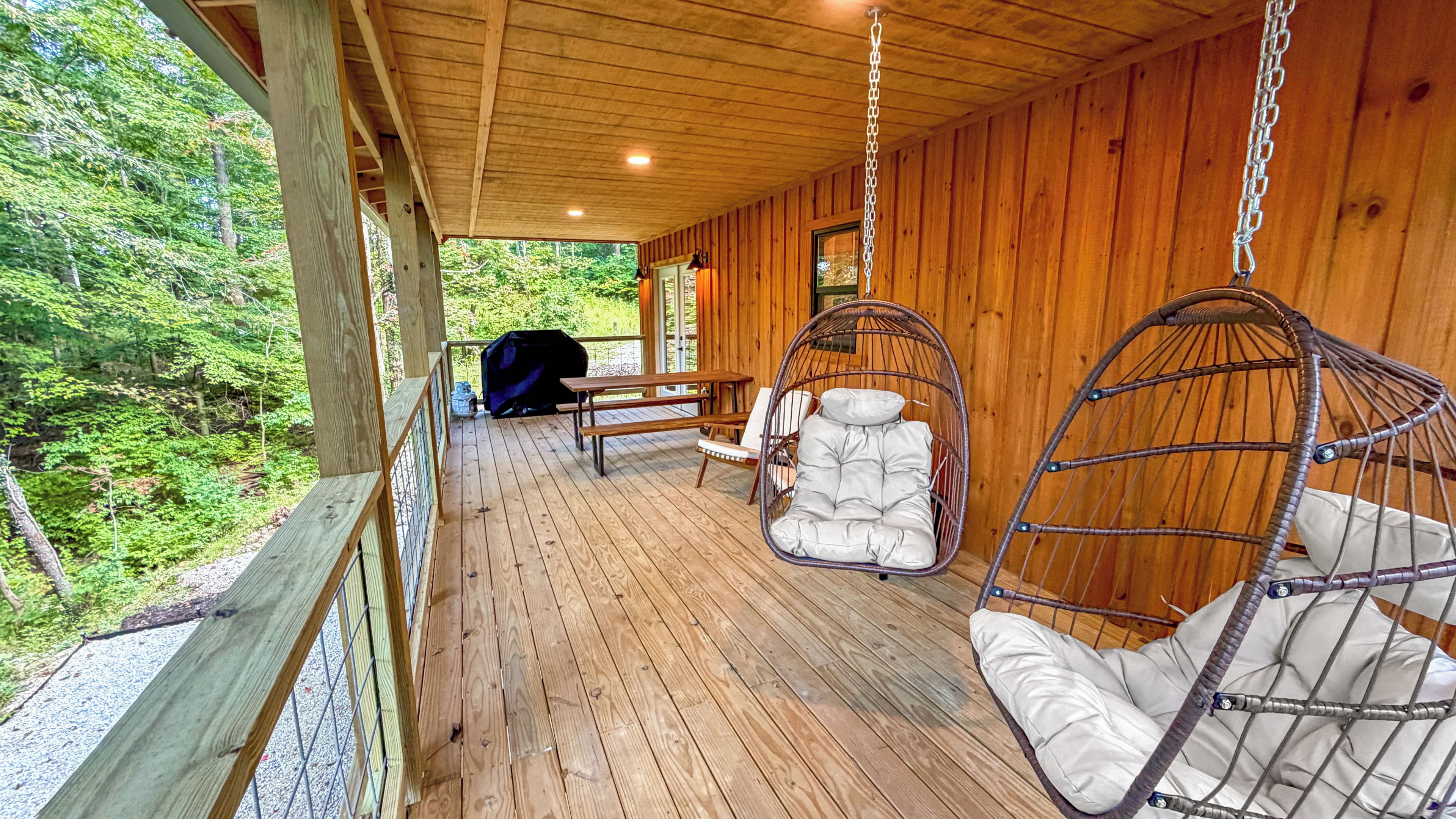 Eine Holzterrasse mit Hängestühlen und einem Picknicktisch.
