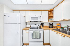 A compact kitchen with white appliances, wooden countertops, and a built-in oven. - Side Ocean View | Heated Pool | Oceans Atrium #1202 (Daytona Beach Shores)