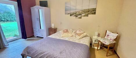 Une chambre à coucher comprenant un lit, une armoire, une table de chevet avec une lampe, une chaise et un tableau accroché au mur.