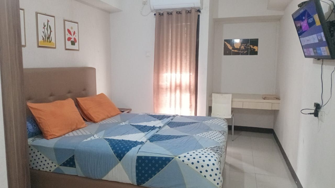 Une chambre à coucher avec un lit, un bureau et un téléviseur.