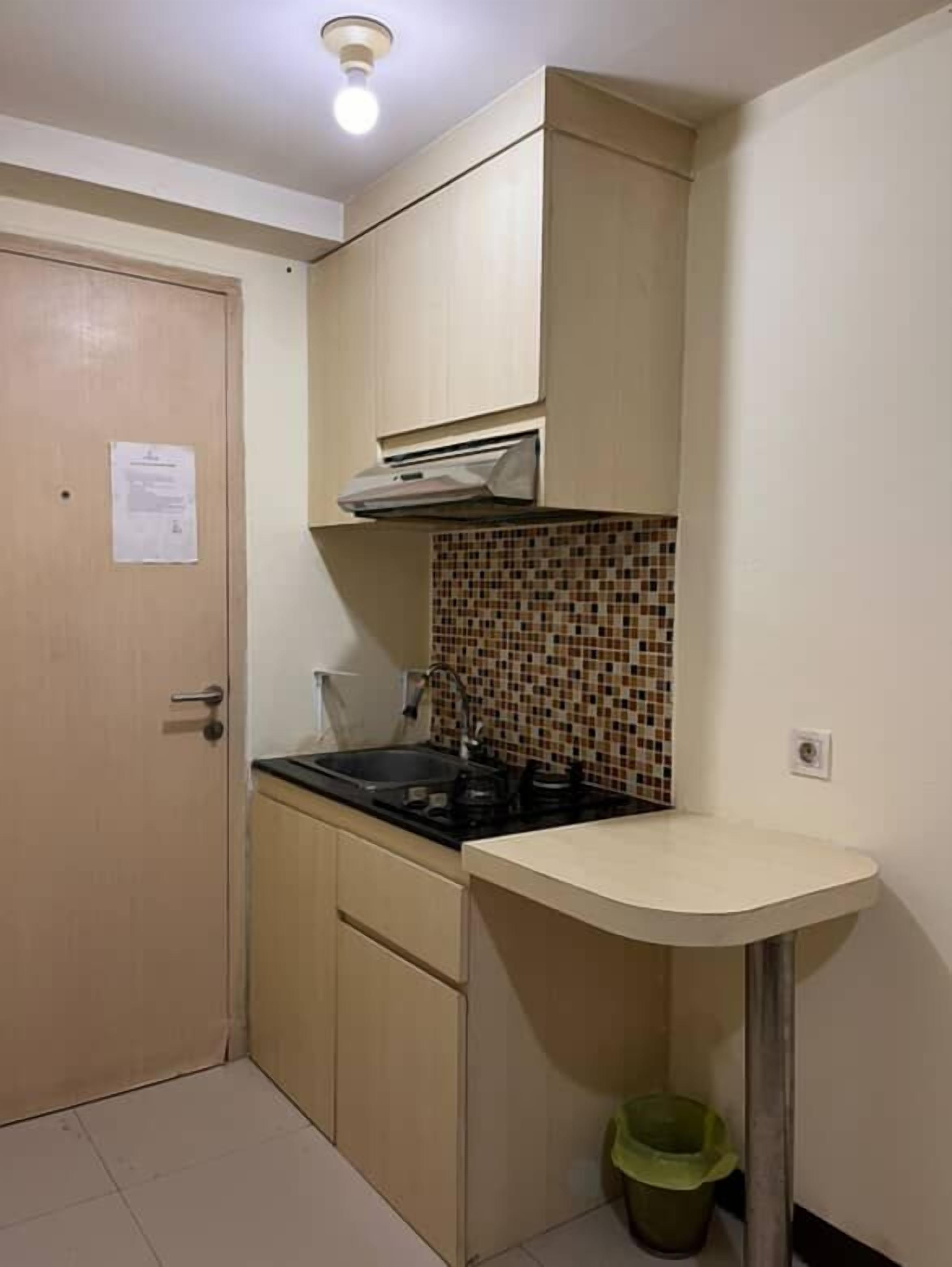 A compact kitchen with a stove, sink, and tiled backsplash.
