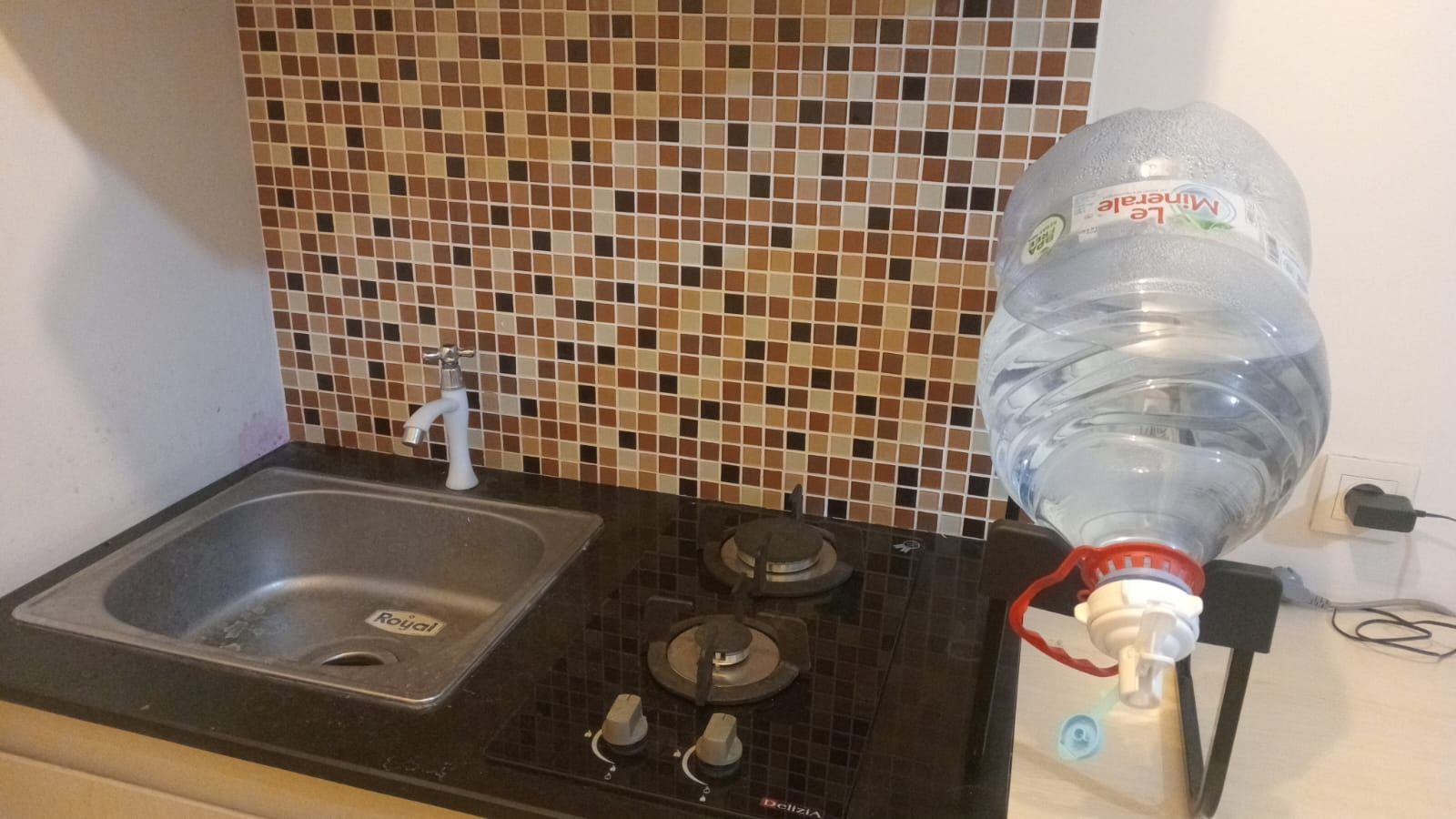 Una cocina equipada con un lavamanos, estufa y dispensador de agua.