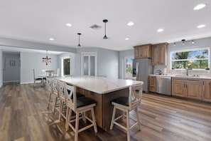 A spacious kitchen with a large island, wooden cabinets, and a view of the outdoors. - 🛥️🌴Private Heated Pool | Bayfront w/ Boat Dock | Lured Away (Fort Myers Beach)