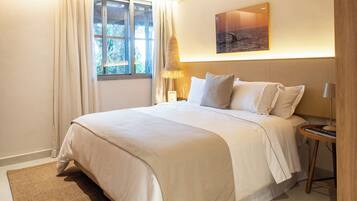 Un dormitorio moderno con una cama grande, una mesita de noche, una lámpara y vistas al exterior a través de una ventana.