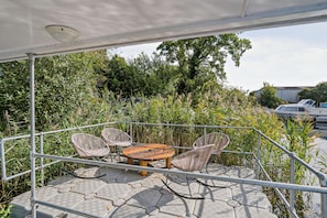 A balcony with a metal railing, a round table, and two wicker chairs. - Host Stay Coot Club (Beccles)